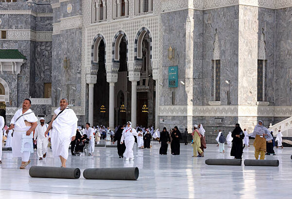 Mecca, Saudi Arabia - April 18, 2011: Muslim pilgrims walk in the courtyard of The Masjid al-Haram ( The Grand Mosque) which is the largest mosque in the world and it surrounds the Kaaba, the place which Muslims worldwide turn towards while performing daily prayers. The Kaaba is the most sacred site in Islam.